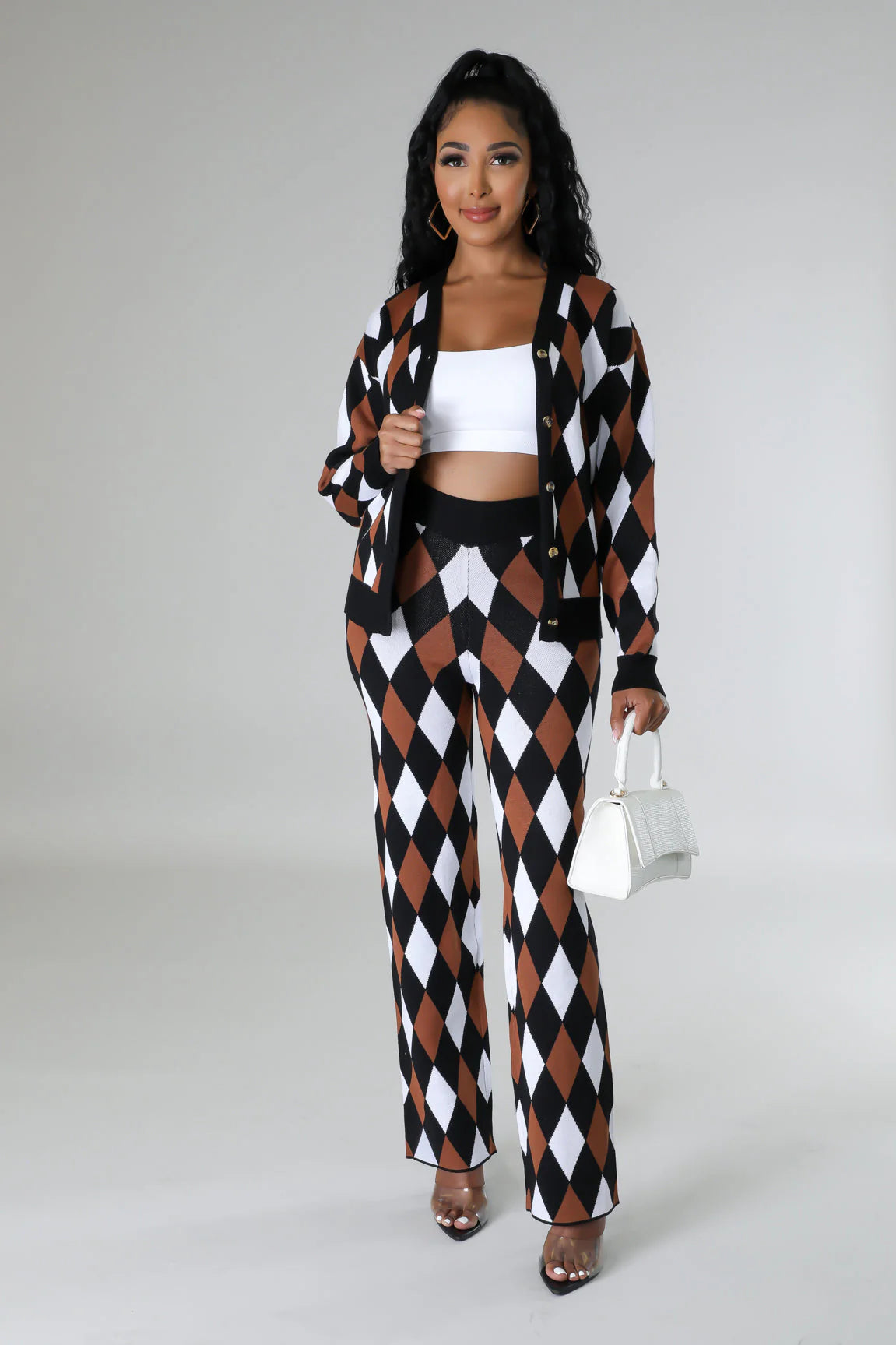 Woman wearing a black, white, and brown checkered outfit with a white top and holding a white handbag.
