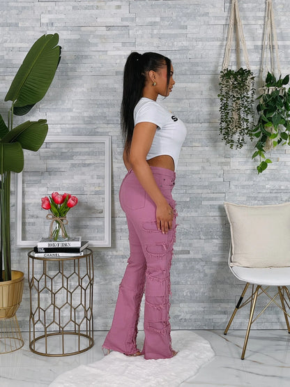 Woman wearing pink pants and a white top in a room with plants and a small table.