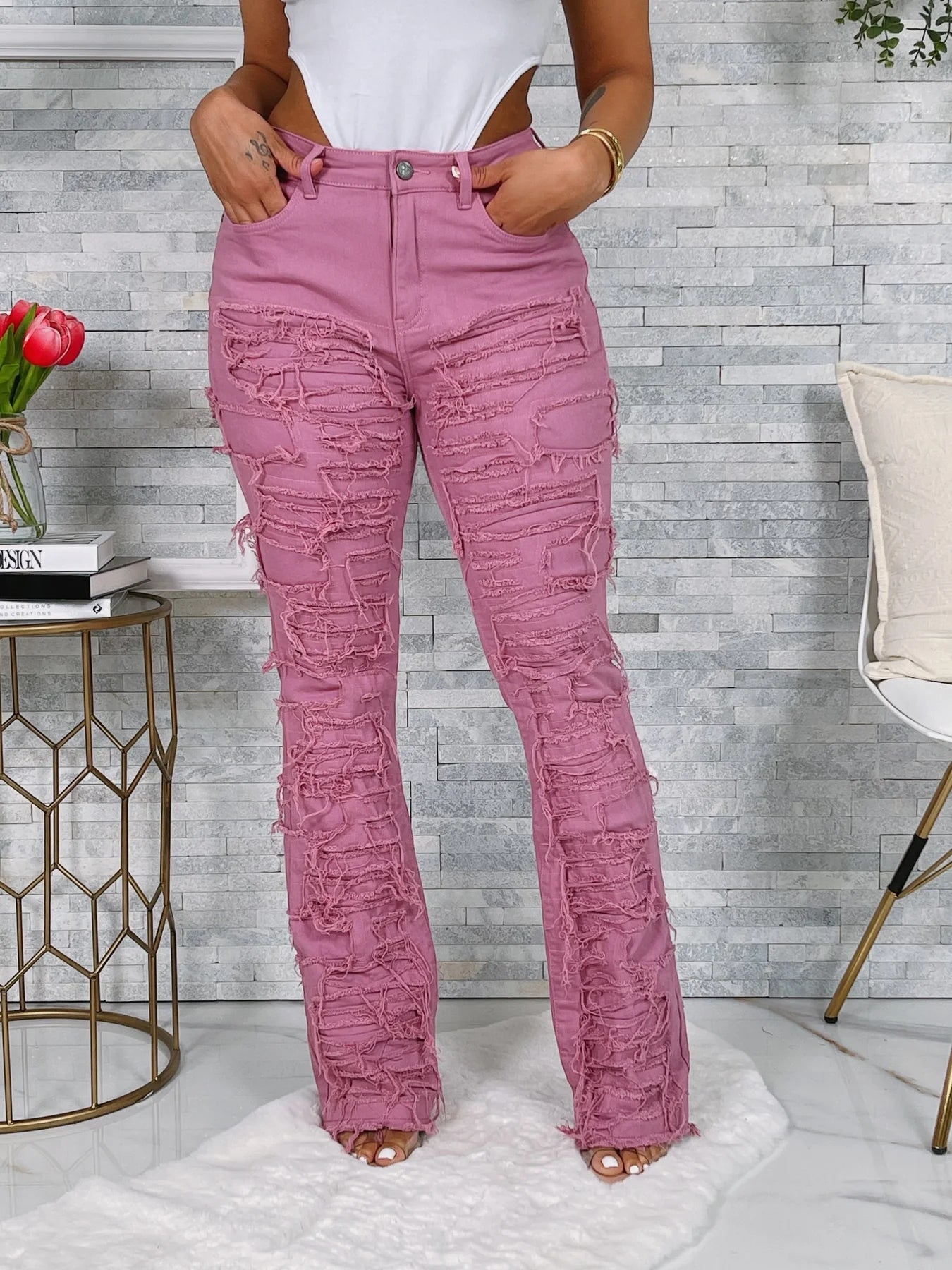 Person wearing pink distressed jeans in a room with a gray textured wall.