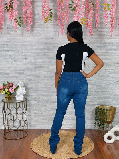 Person wearing blue jeans and a black top standing in a room with decorative flowers and furniture.